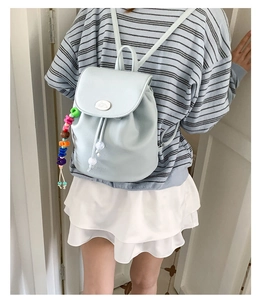 Detail of mint green lychee faux leather backpack with drawstring closure and colorful charm