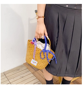 Detail of woven straw handbag with colorful braided rope handles and drawstring lining