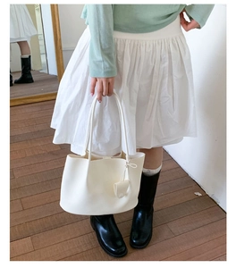 Detailaufnahme der weißen Leder-Shopper mit Lychee-Narbenstruktur und passendem Anhänger