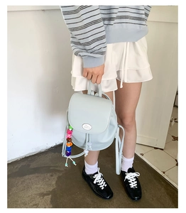 Close-up of mint blue mini backpack featuring colorful rainbow bead charm and flap closure