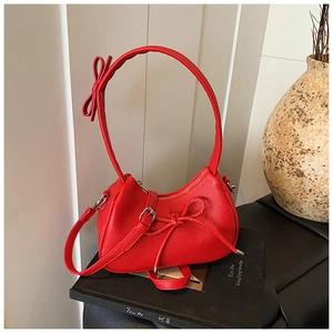Detail of red crescent bag with lychee texture and decorative 3D bow on the strap
