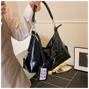 Close-up of black patent leather tote bag with woven handle and silver hardware detail