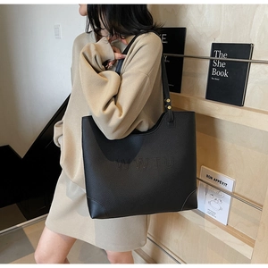 Detailed macro view of black lychee grain leather tote bag with embossed WWTU lettering