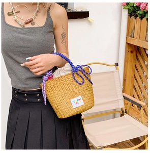 Detail of hand-woven straw tote with vibrant blue rope handles and drawstring lining