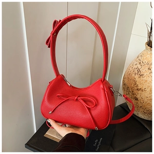 Detail of red crescent bag showing lychee leather texture and 3D ribbon bow accents