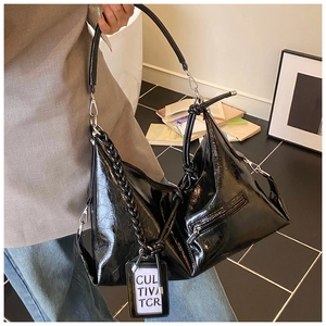 Detail view of black oily leather hobo bag with woven chain and side zipper pocket