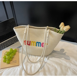Detail of white woven tote bag featuring rainbow summer embroidery and rope texture