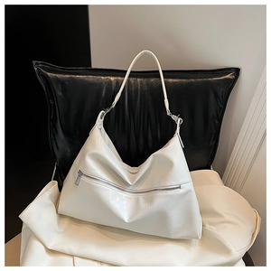 Detail of a beige hobo bag with a zipper design on a stylish leather surface
