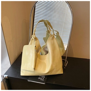 Detail of light yellow textured hobo tote bag with woven handle and small zipper pouch