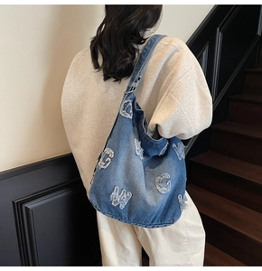 Detail of vintage denim tote bag featuring distressed letter patches and soft texture