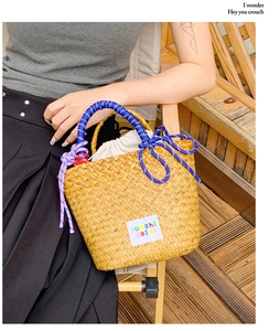 Close-up of woven straw tote bag featuring blue and white rope handles and inner drawstring