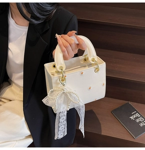 Detail of white PU mini handbag with daisy embroidery and pearl bow charm accessory