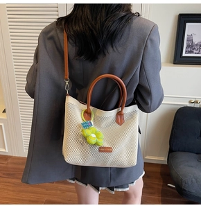 Détail du sac fourre-tout en maille crème avec poignées en cuir et breloque tournesol vert