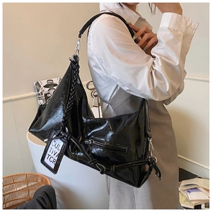 Detail of black glossy leather tote bag with braided handle and metallic accents