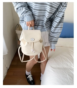 Detail of cream white leather backpack featuring a cute rabbit logo and drawstring closure