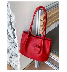 Detail der roten Ledershopper mit Lychee-Struktur und Schultergurten auf einem Stuhl