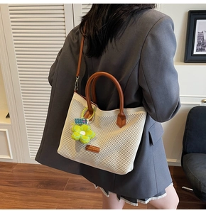 Détail du sac cabas tissé avec lanières en cuir marron et pendentif fleur verte