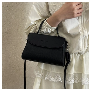 Gros plan sur le sac bandoulière noir texture litchi montrant le détail du cuir grainé