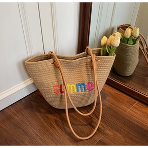 Detail of woven straw tote bag with summer embroidery and brown leather straps