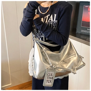 Detail of silver metallic large tote bag with braided handle and side drawstring knot