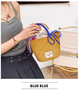 Detail of woven straw tote bag featuring blue rope handles and drawstring lining bag