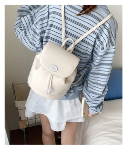 Lifestyle shot of a beige drawstring backpack with contrast trim and cute cartoon patch