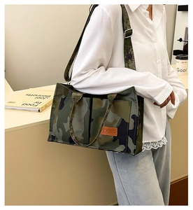 Detail view of a large camouflage tote bag featuring a bright orange TXBD leather patch label