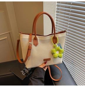 Détail du sac cabas tissé blanc cassé avec lanières en cuir marron et fleur