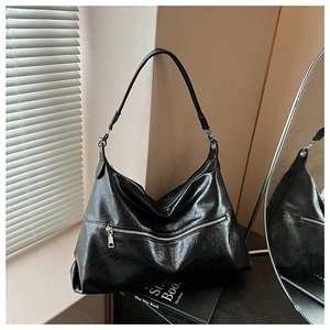Detail of black shoulder bag with cracked leather texture and silver zipper accents