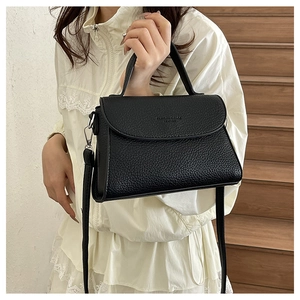 Détail d'un sac bandoulière en cuir noir grainé avec bandoulière réglable et texte embossé