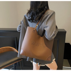 Brown leather tote bag featuring WWTU embossed letters and golden metal rivets detail