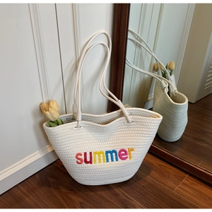 Close-up of white woven tote bag featuring colorful summer embroidery on wood floor