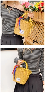Detailed view of handmade woven straw bucket bag with colorful rope handles and label