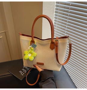 Détail du sac fourre-tout tissé crème avec garniture en cuir marron et pendentif fleur