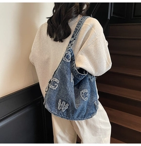 Detail of vintage denim tote bag showing letter embroidery and metallic chain buckle
