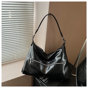 Detail of glossy black leather tote with silver zipper and natural creased texture