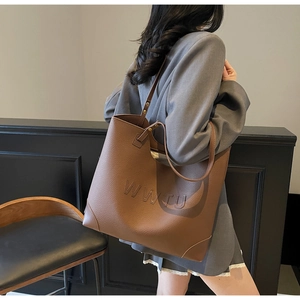 Detail of WWTU embossed lettering on vintage brown lychee grain leather tote bag