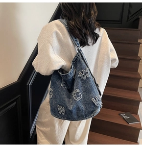 Detailed close-up of blue wash denim tote bag with distressed vintage letter patches