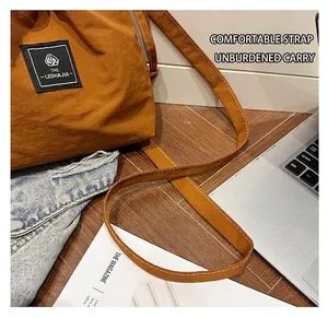 Close-up of mustard yellow bucket bag with brand tag and adjustable shoulder strap