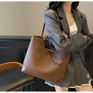 Detail of embossed WWTU lettering on brown lychee texture leather tote bag