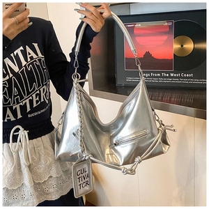 Detail view of silver metallic hobo bag featuring woven rope strap and hanging logo charm