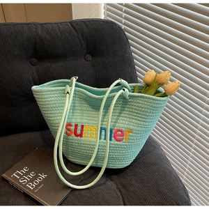 Detail of light blue woven tote bag with colorful summer embroidery and floral decor