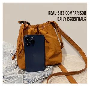 Size comparison of orange drawstring crossbody bag with smartphone showing capacity
