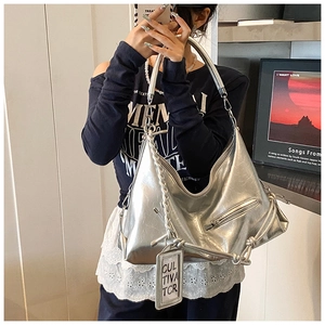 Detail of silver metallic hobo bag featuring decorative tags and textured chain strap