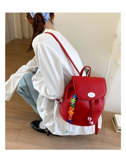 Detail of red pebbled leather bucket backpack with rabbit logo and charm on model