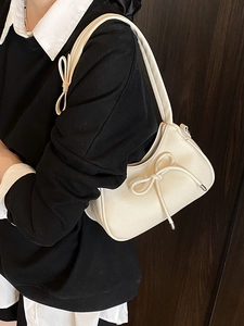 Beige bow hobo bag with lychee texture and compact shoulder strap on a model