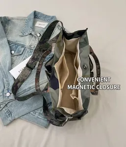 Detail view of the interior multi-pocket layout and magnetic buckle of camouflage tote bag