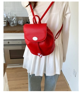 Detail of red pebbled leather mini backpack with drawstring closure and flap on a model