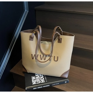 Detailed macro view of WWTU letter embossing on two-tone beige leather tote bag