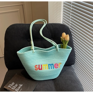 Detail of blue woven beach tote with vibrant summer colorful letter embroidery